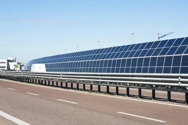 Eine mit PV-Modulen bestückte Lärmschutzwand steht am Rande einer mehrspurigen Straße