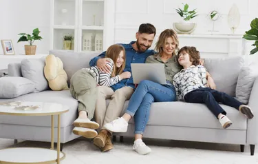 Eine vierköpfige Familie sitzt eng aneinander gekuschelt auf einem Sofa