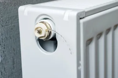 Nahaufnahme eines geöffneten Heizungsventils aus dem ein kleiner Wasserstrahl herausschießt