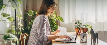 Eine Frau sitzt am Laptop und tippt auf der Tastatur.