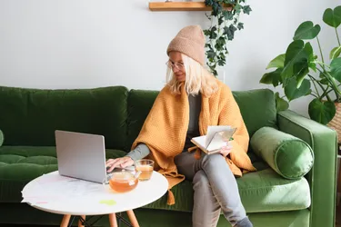 Eine Frau sitzt auf einem Sofa und arbeitet an einem Laptop