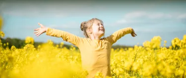 Ein kleines Mädchen steht im Rapsfeld