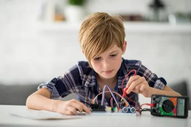 Ein Junge prüft mit einem Multimeter den Stromfluss in einem Stromkreis