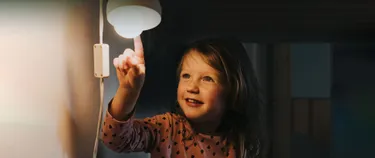 Mädchen zeigt auf eine Glühbirne