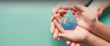 Hände halten einen Wassertropfen.