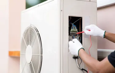 Nahaufnahme einer Wärmepumpe an der ein Techniker Einstellungen vornimmt