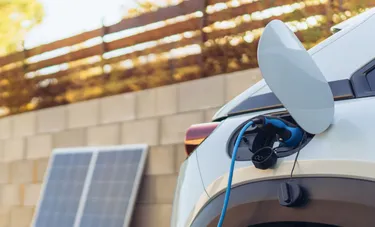 Nahaufnahme einer E-Auto-Tankklappe, in die eine Ladebuchse eingesteckt wird