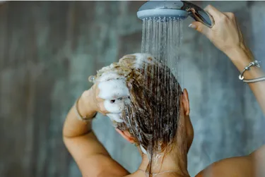 Frau wäscht sich unter der Dusche die Haare
