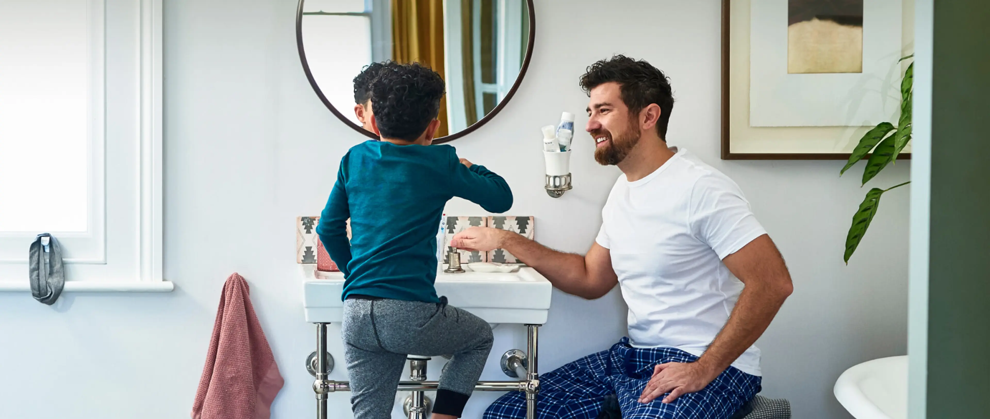 Vater und Sohn stehen gemeinsam im Badezimmer vor einem Waschbecken