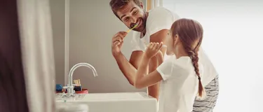 Ein Vater und seine Tochter putzen zusammen ihre Zähne.