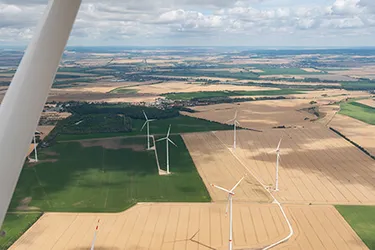 Blick über einen Windpark aufgenommen in luftiger Höhe vom Dach einer Windkraftanlage