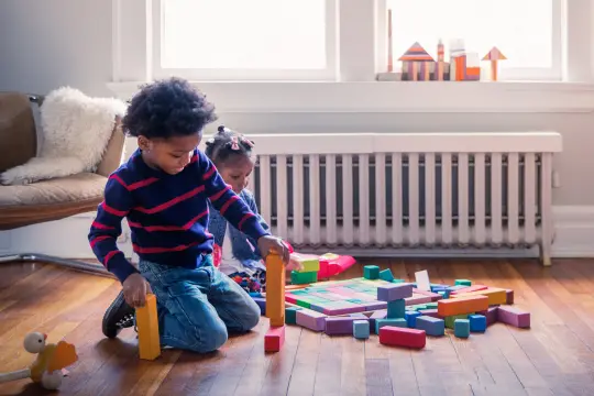 Kinder spielen sitzend auf dem Fußboden.